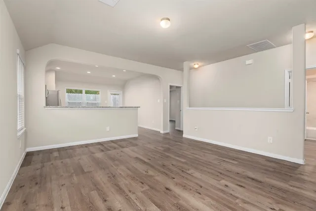 an empty room with wooden floor and windows