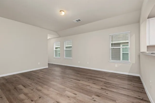 a view of an empty room with wooden floor and a window