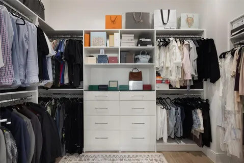 a view of walk in closet with clothes and shoes