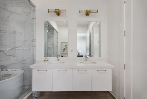 a bathroom with a double vanity sink mirror and bathtub