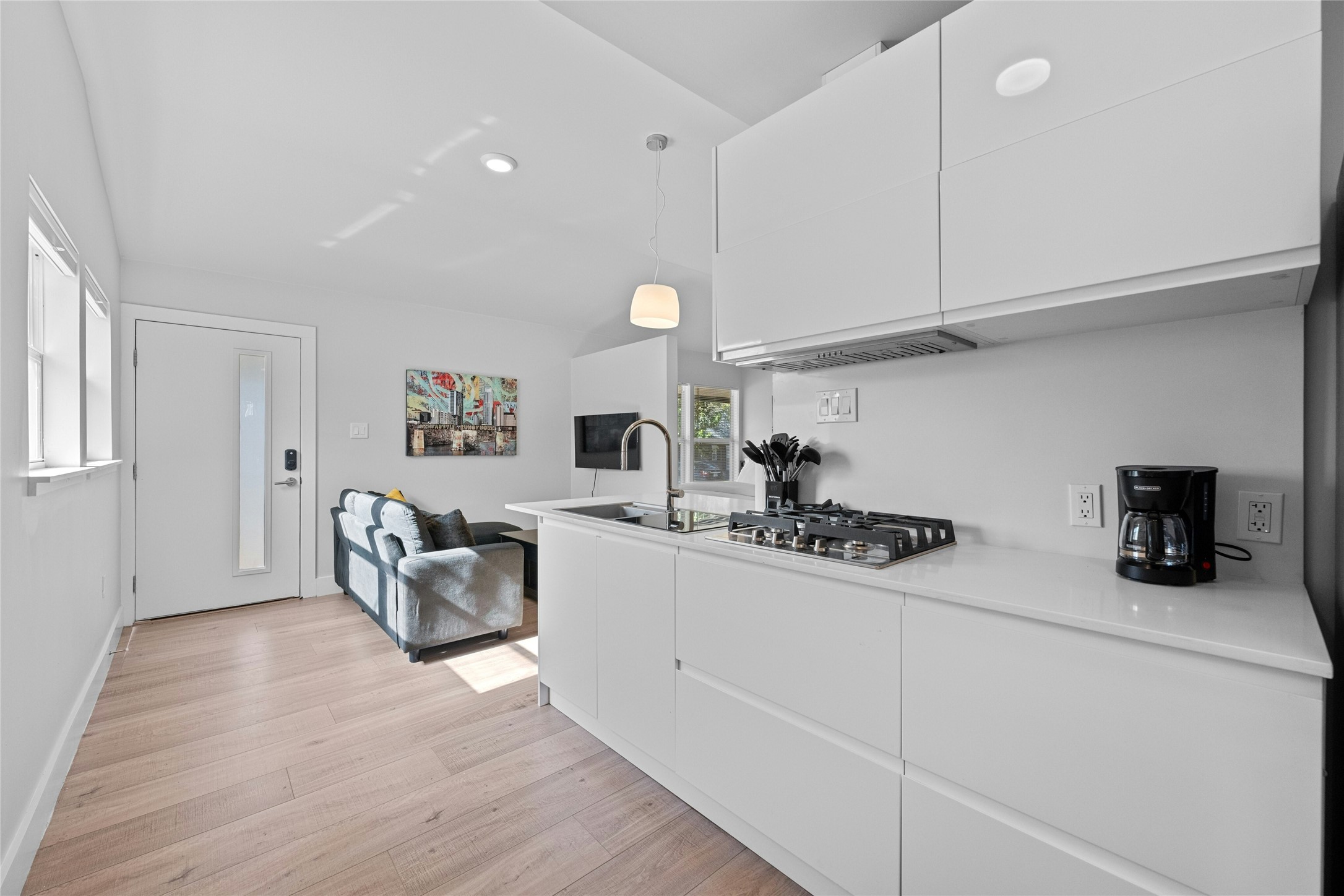 2201 Leon Street, Unit D Austin, TX 78705 - Photo 12 of 24 a kitchen with stainless steel appliances granite countertop a sink dishwasher stove and white cabinets with wooden floor