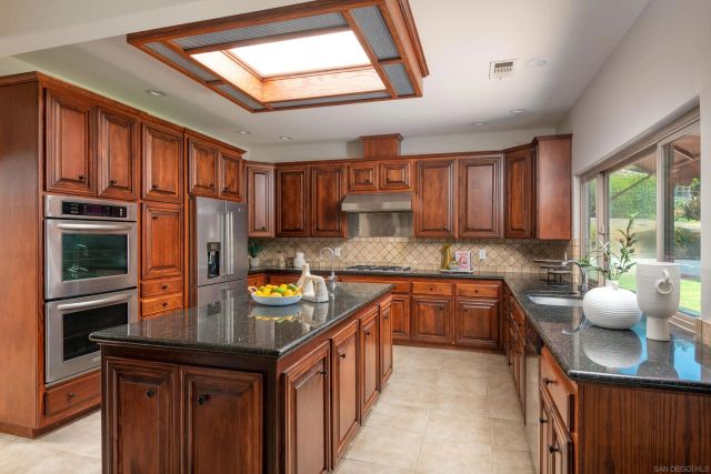 a kitchen with stainless steel appliances granite countertop a sink a stove and a refrigerator