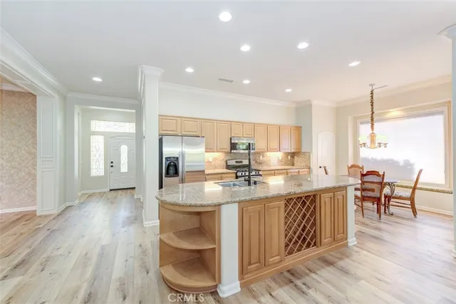 a kitchen with kitchen island granite countertop a table chairs sink and cabinets
