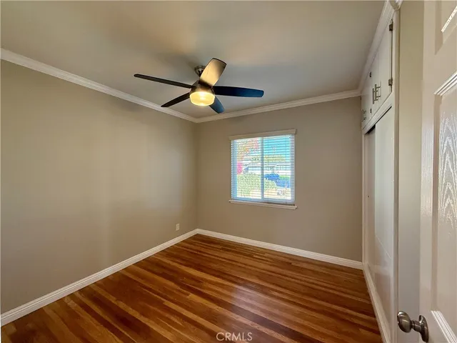 a view of a room with wooden floor and a ceiling fan