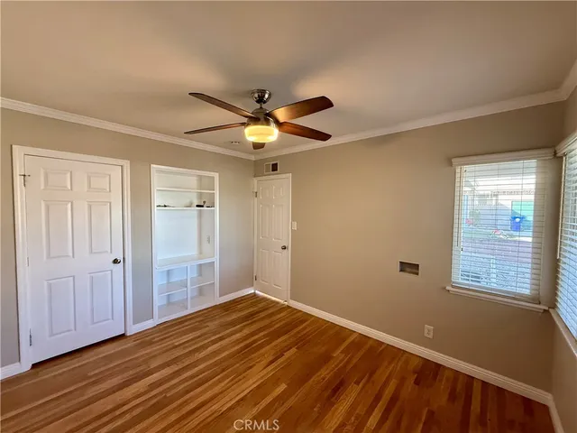 a view of empty room with wooden floor and fan