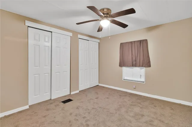 an empty room with a ceiling fan and a window