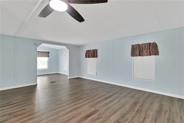 an empty room with wooden floor cabinet and windows