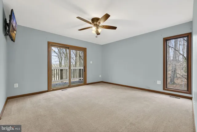 an empty room with chandelier fan and windows