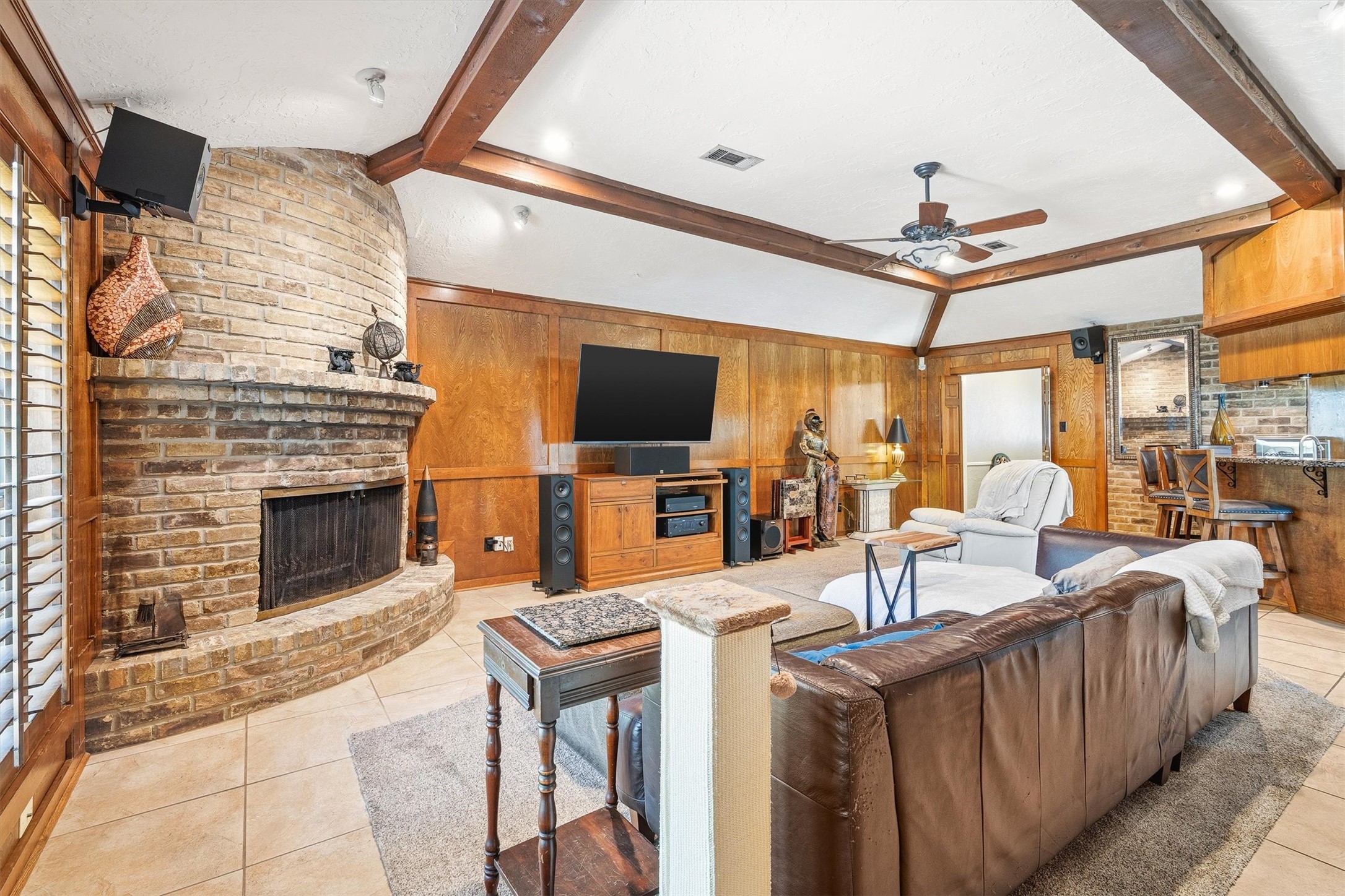 826 North Rivershire Drive Conroe, TX 77304 - Photo 7 of 46 This angle tells the whole story — that curved brick fireplace is a genuine showstopper, anchoring a room that was clearly designed for living well. Notice the speakers and the glimpse of the wet bar area just beyond, because this home was wired for a good time.