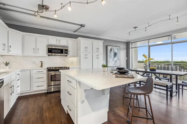 a kitchen with stainless steel appliances kitchen island granite countertop a stove a sink a dining table and chairs with wooden floor