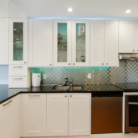 a kitchen with granite countertop a sink and a white cabinets