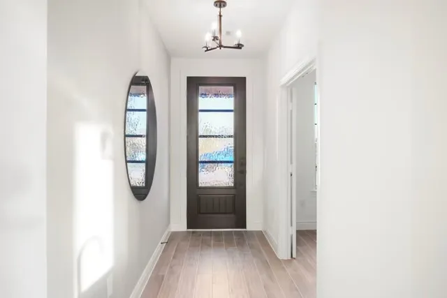 a view of a hallway with windows and chandelier