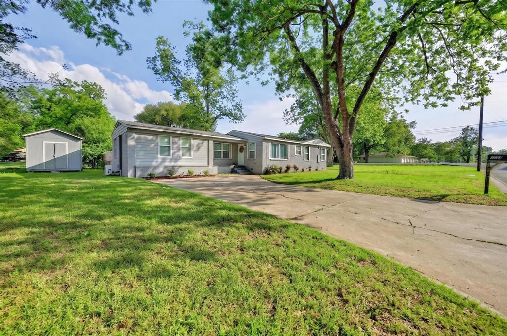 Ranch-style residence featuring light gray siding, white trim windows, and a paved driveway