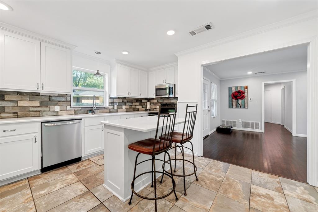 505 Laurel Road Athens, TX 75751 - Photo 13 of 32 Modern kitchen featuring white cabinetry, stainless steel appliances, a white island, mosaic tile backsplash, and tile flooring