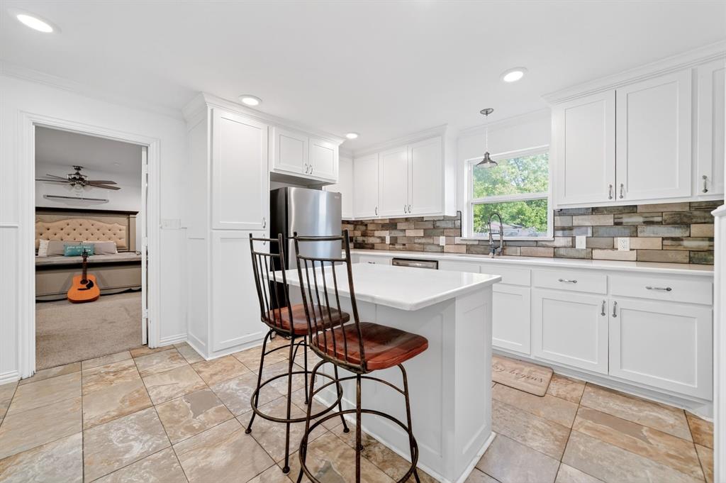505 Laurel Road Athens, TX 75751 - Photo 14 of 32 Modern kitchen featuring white shaker cabinetry, stainless steel appliances, a multi-tone tile backsplash, and an island with seating