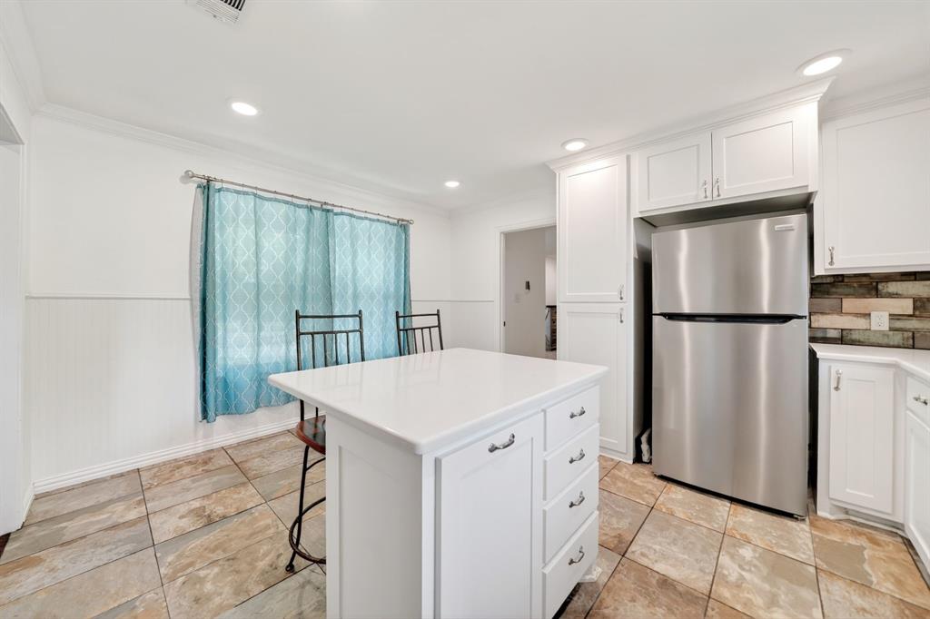 505 Laurel Road Athens, TX 75751 - Photo 15 of 32 Kitchen featuring a central island with a solid surface countertop, white cabinetry with silver hardware, stainless steel refrigerator, and stone tile flooring