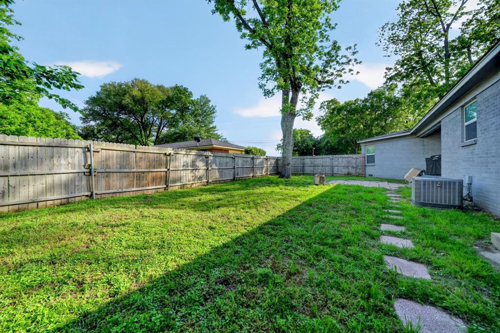 505 Laurel Road Athens, TX 75751 - Photo 30 of 32 Fenced backyard featuring natural grass, mature trees, a stone paver pathway, and a brick exterior building