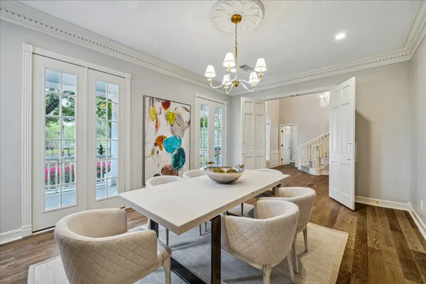 a dining room with wooden floor a chandelier a wooden table and chairs