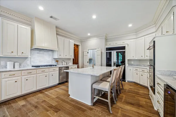 a kitchen with stainless steel appliances kitchen island granite countertop a stove top oven a sink a counter space and cabinets