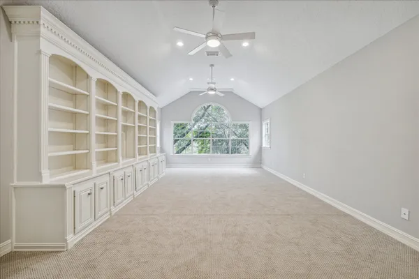 an empty room with ceiling fan and window