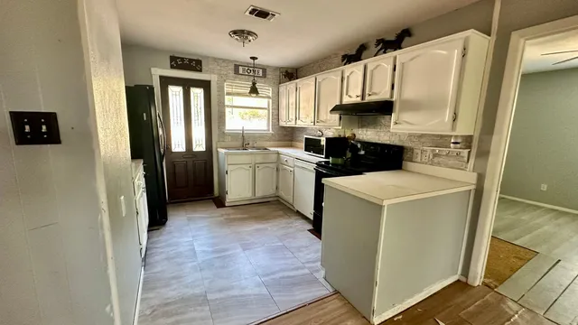 a kitchen with a sink a refrigerator a stove top oven and cabinets