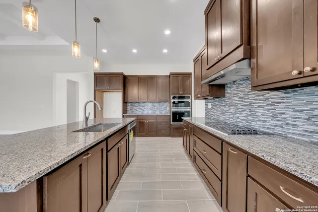 a kitchen with stainless steel appliances granite countertop a sink a counter top space cabinets and a wooden floor