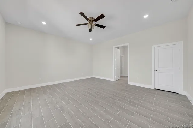 wooden floor in an empty room with a ceiling fan