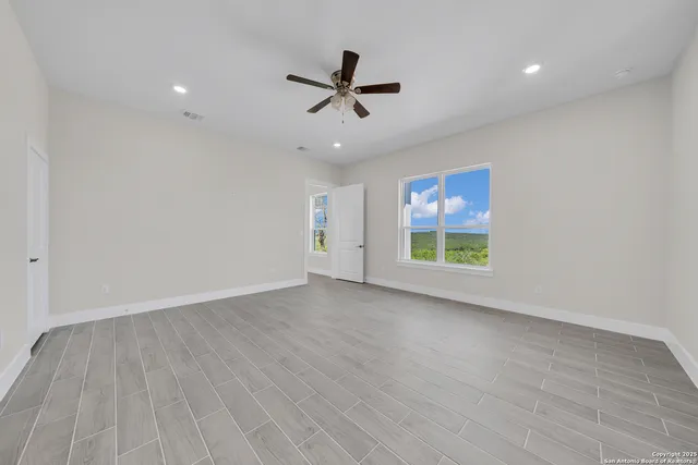 a view of an empty room with a window and wooden floor