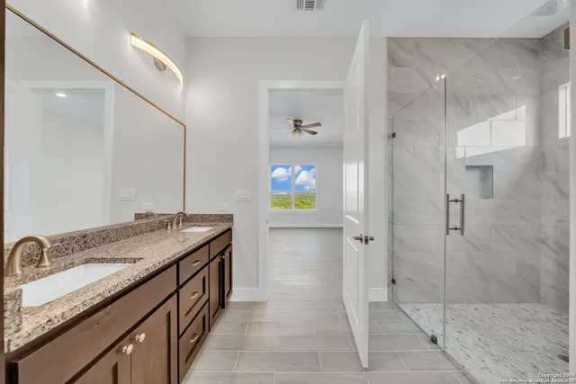 a bathroom with a granite countertop sink a mirror and shower