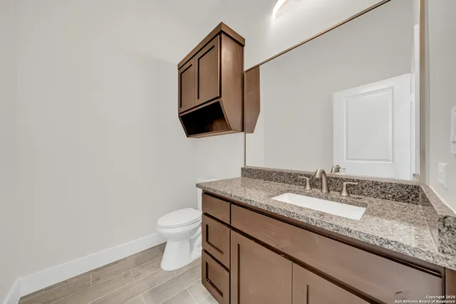 a bathroom with a granite countertop sink a toilet and mirror