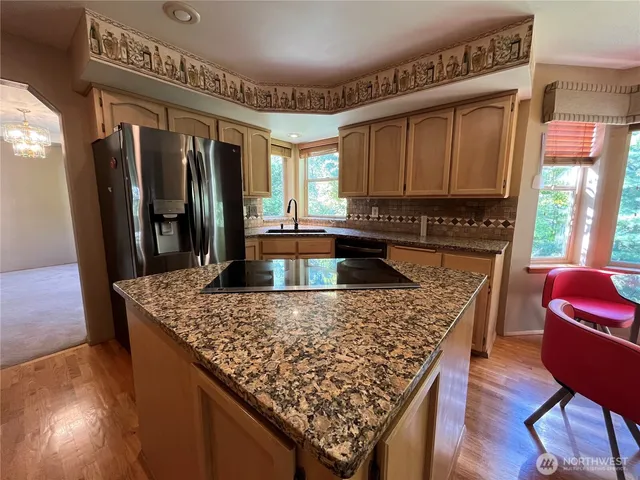 a open kitchen with stainless steel appliances granite countertop a refrigerator dining table and chairs