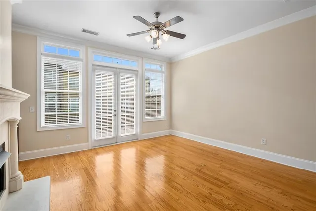 a view of an empty room with a window and wooden floor