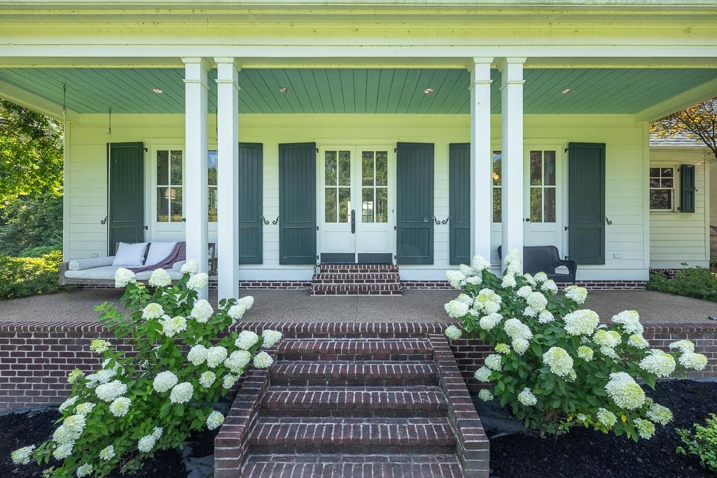 1915 Teague Store Road Somerville, TN 38068 - Photo 2 of 38 Front porch entry featuring brick steps, a brick foundation, four white columns, a light teal porch ceiling, and white blooming hydrangeas