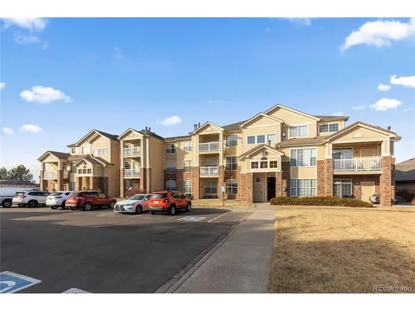 a view of building with cars parked across