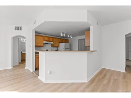 a kitchen with a refrigerator and a wooden floor