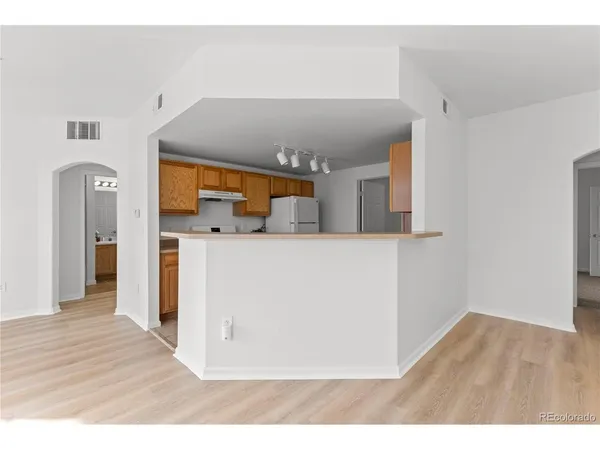 a kitchen with a refrigerator and a wooden floor