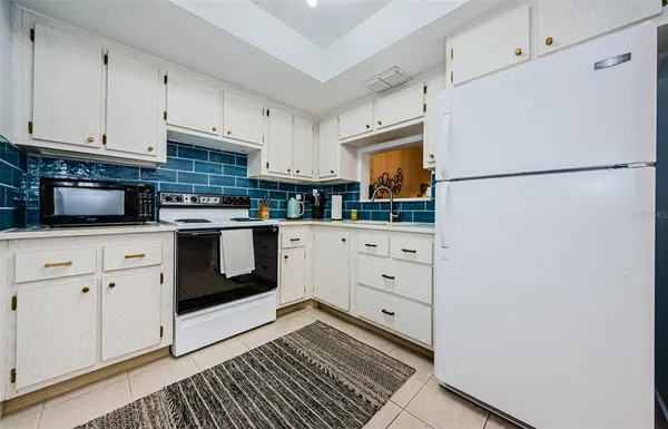 a kitchen with granite countertop white cabinets and white appliances