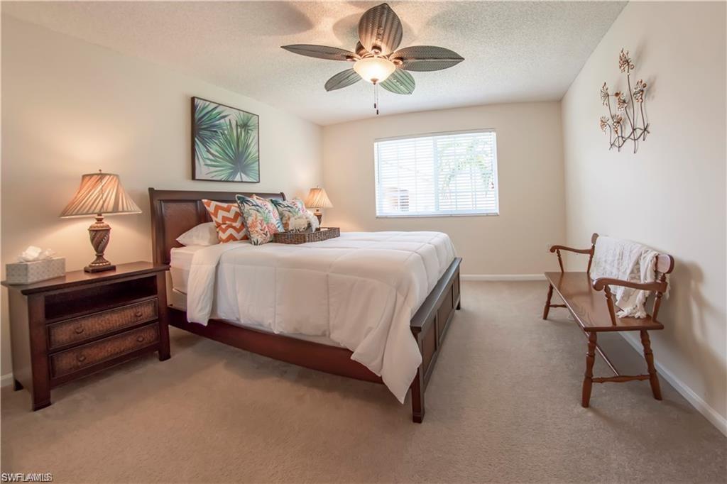 1220 Wildwood Lakes Boulevard, Unit 201 Naples, FL 34104 - Photo 19 of 35 Carpeted bedroom featuring a textured ceiling and ceiling fan