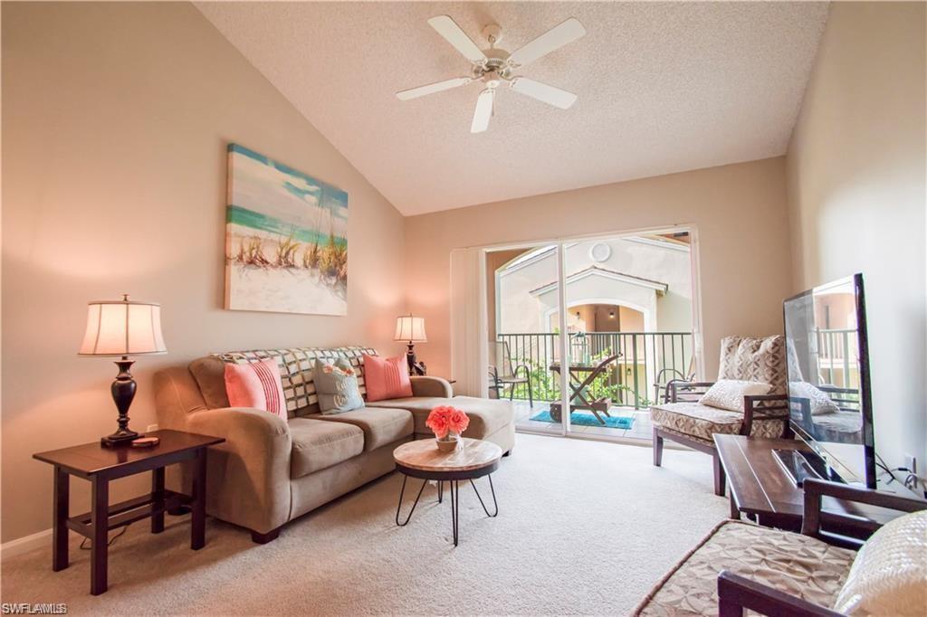 1220 Wildwood Lakes Boulevard, Unit 201 Naples, FL 34104 - Photo 2 of 35 Living room featuring a textured ceiling, light carpet, ceiling fan, and vaulted ceiling