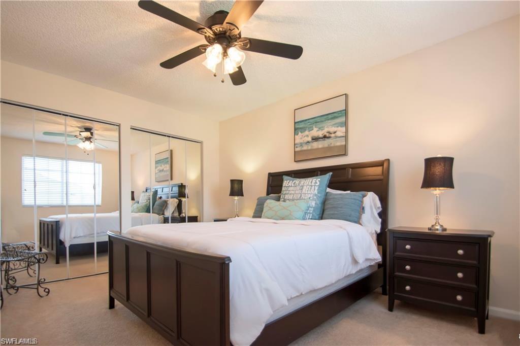 1220 Wildwood Lakes Boulevard, Unit 201 Naples, FL 34104 - Photo 21 of 35 Bedroom featuring multiple closets, ceiling fan, light carpet, and a textured ceiling
