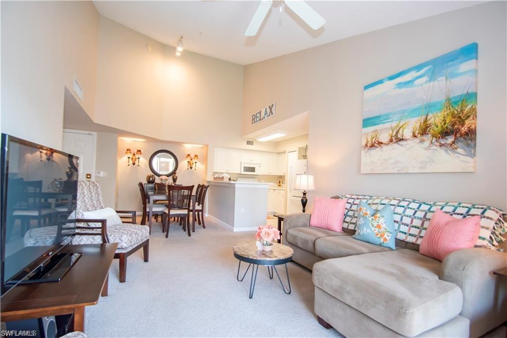 1220 Wildwood Lakes Boulevard, Unit 201 Naples, FL 34104 - Photo 3 of 35 Carpeted living room featuring high vaulted ceiling and ceiling fan