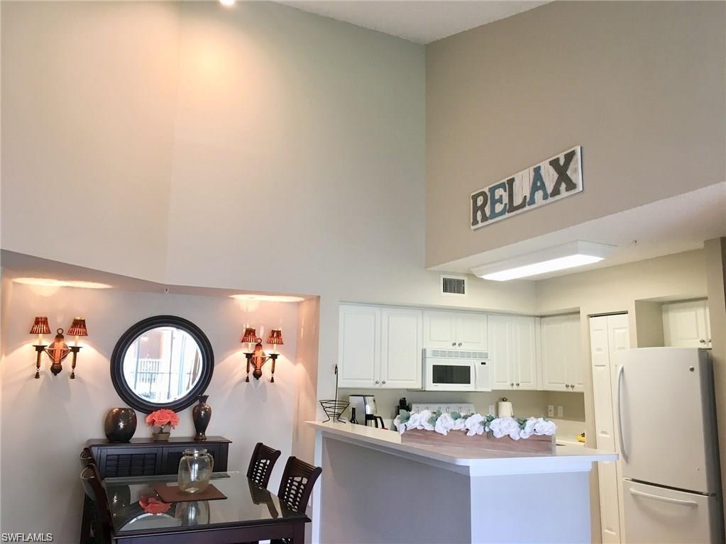 1220 Wildwood Lakes Boulevard, Unit 201 Naples, FL 34104 - Photo 5 of 35 Kitchen with white cabinets, white appliances, and kitchen peninsula