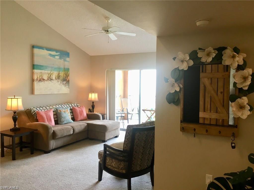 1220 Wildwood Lakes Boulevard, Unit 201 Naples, FL 34104 - Photo 7 of 35 Carpeted living room with ceiling fan and lofted ceiling