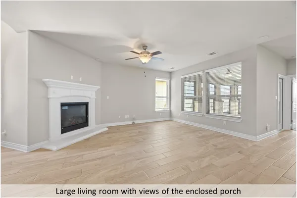a view of an empty room with chandelier fan and windows
