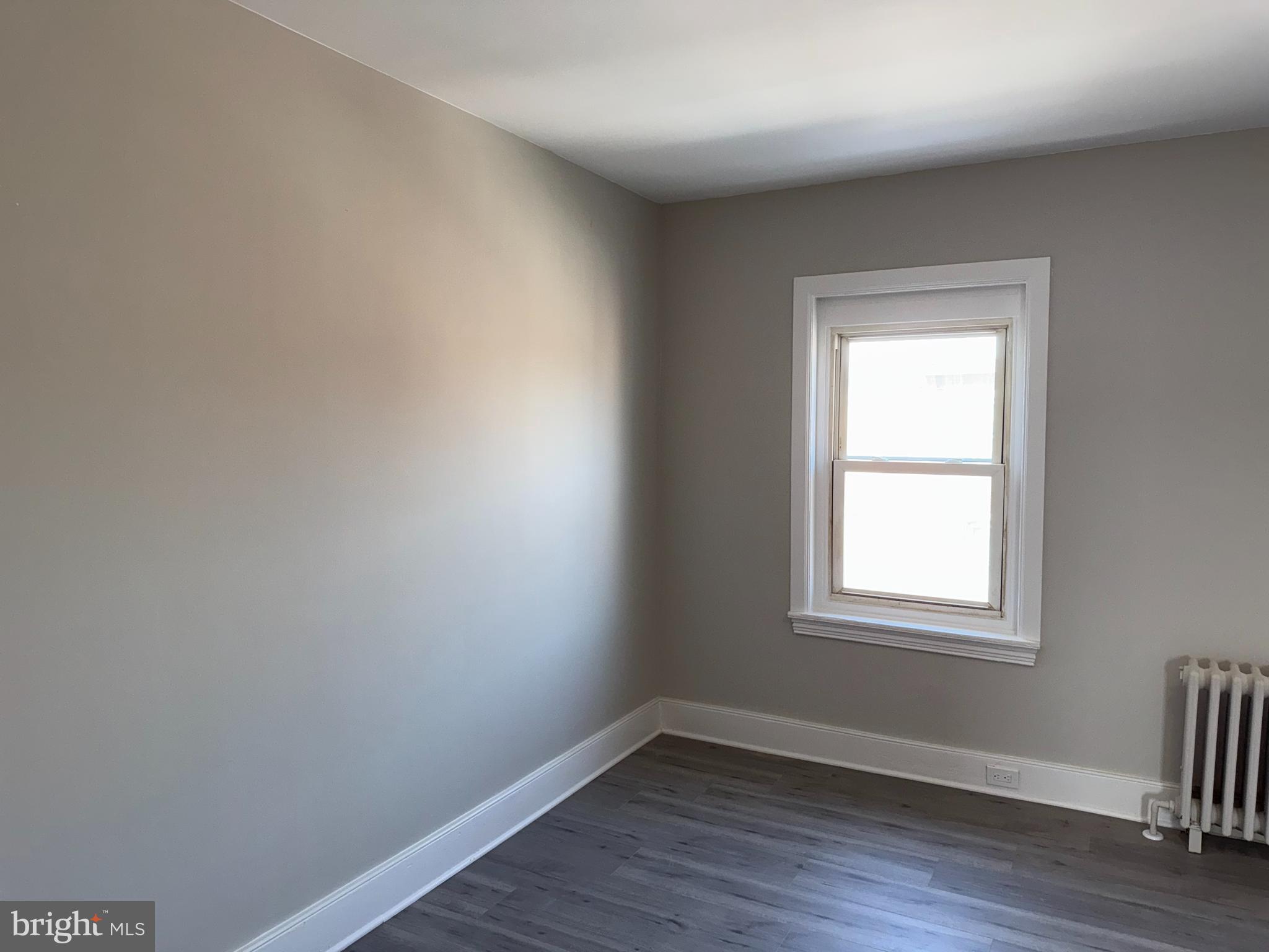 706 Chain Street, Unit 3 Norristown, PA 19401 - Photo 3 of 15 an empty room with wooden floor and windows