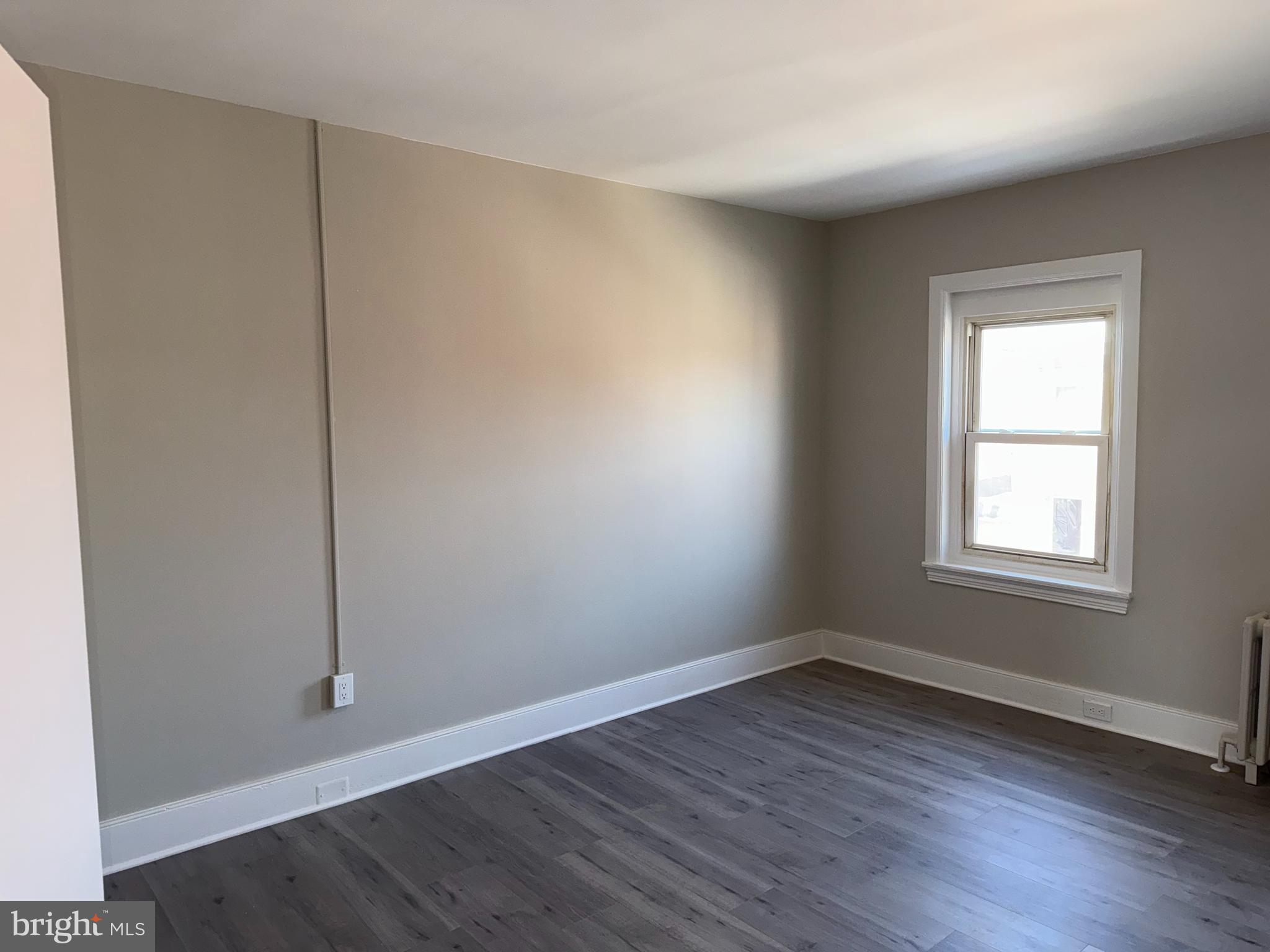 706 Chain Street, Unit 3 Norristown, PA 19401 - Photo 5 of 15 an empty room with wooden floor and windows