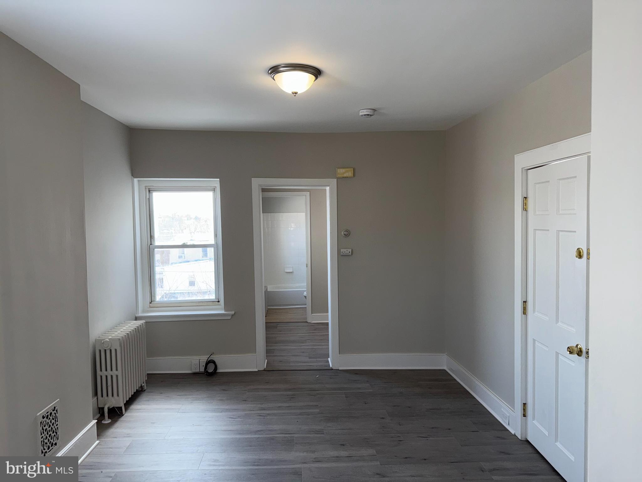 706 Chain Street, Unit 3 Norristown, PA 19401 - Photo 6 of 15 an empty room with wooden floor and windows