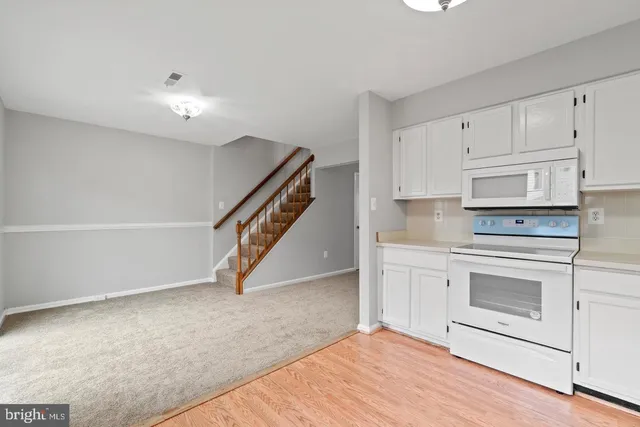 a kitchen with white cabinets and appliances