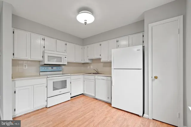 a kitchen with cabinets appliances wooden floor and a window
