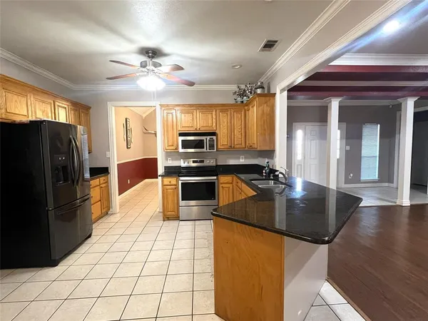 a kitchen with stainless steel appliances granite countertop a refrigerator a stove top oven a sink a dining table and chairs